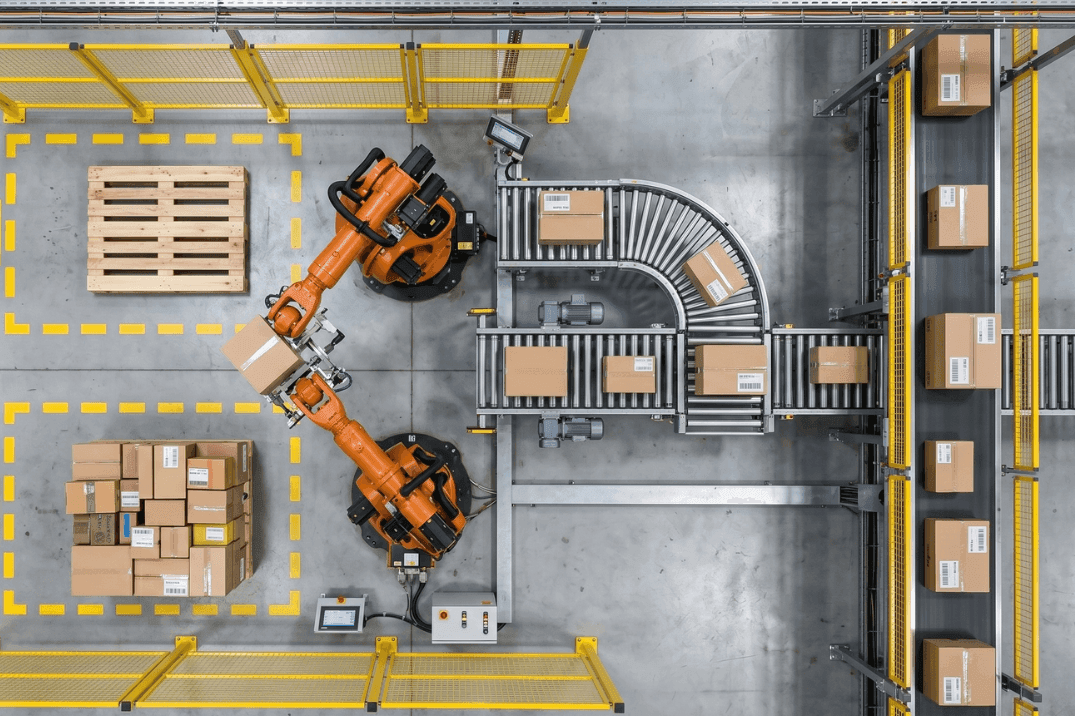 Top-down view of robotic arms picking cartons from a conveyor system, illustrating integration between robotics and conveyor flow in automated warehouse operations